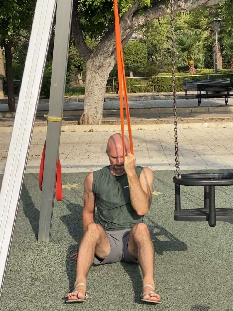 Living a Strong, Calm, and Deeply Alive Life 1 Markus doing a one-arm pull-down with elastic band on a playground in Noto, Sicily